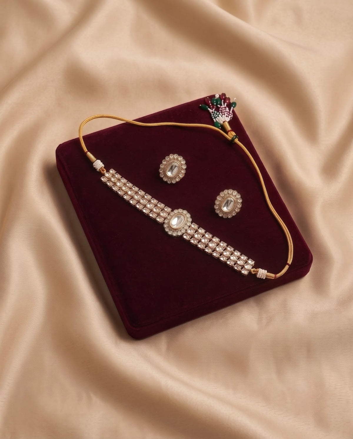 Ivory Pearl Kundan Choker Set with matching earrings displayed on a maroon velvet jewelry tray.