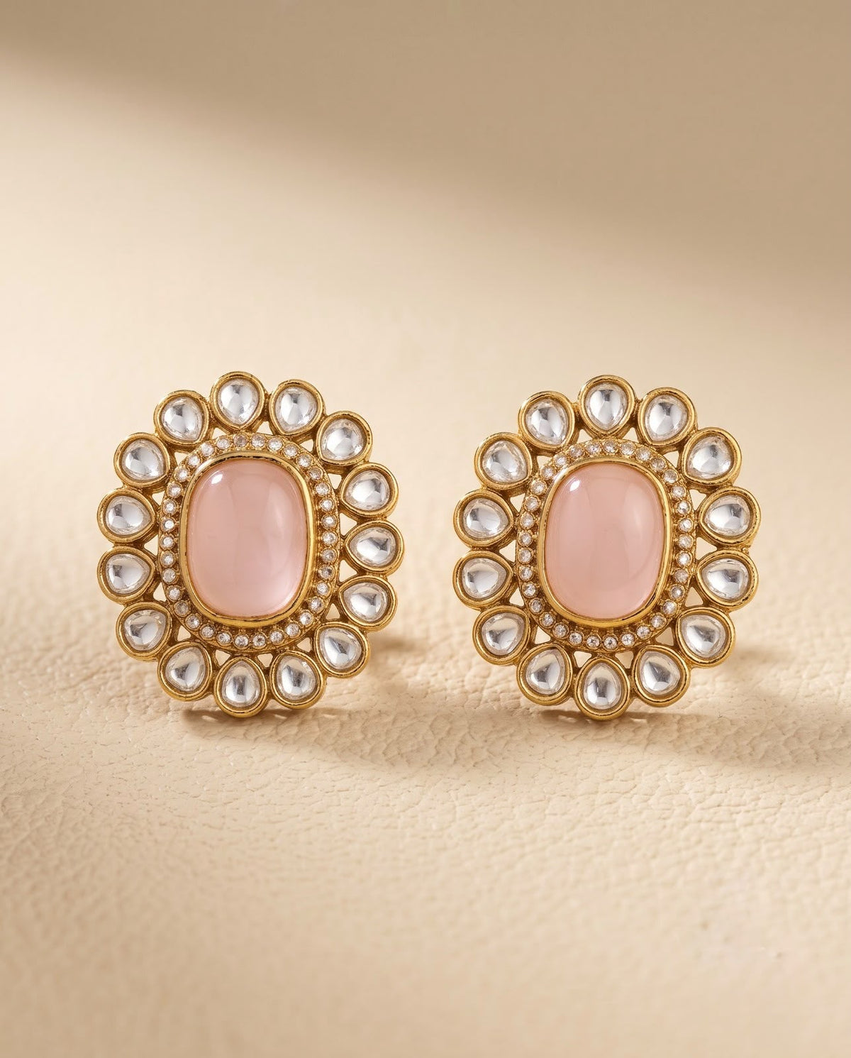 Close-up of pink kundan style stud earrings with gold-tone detailing
