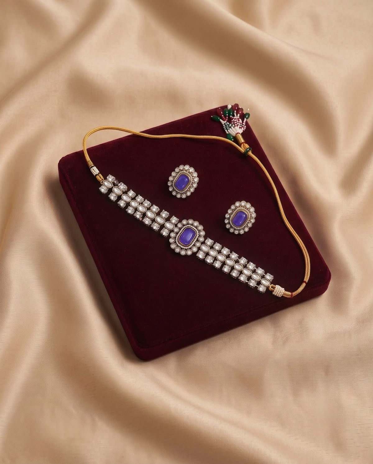 Blue kundan choker necklace set with matching earrings on burgundy velvet