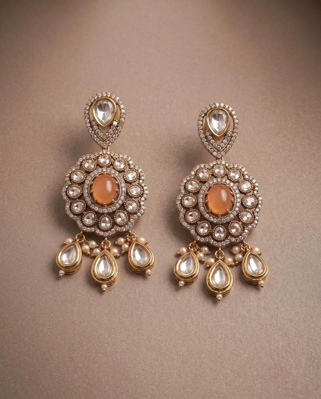 Close-up peach kundan style earrings with pearl and teardrop detailing