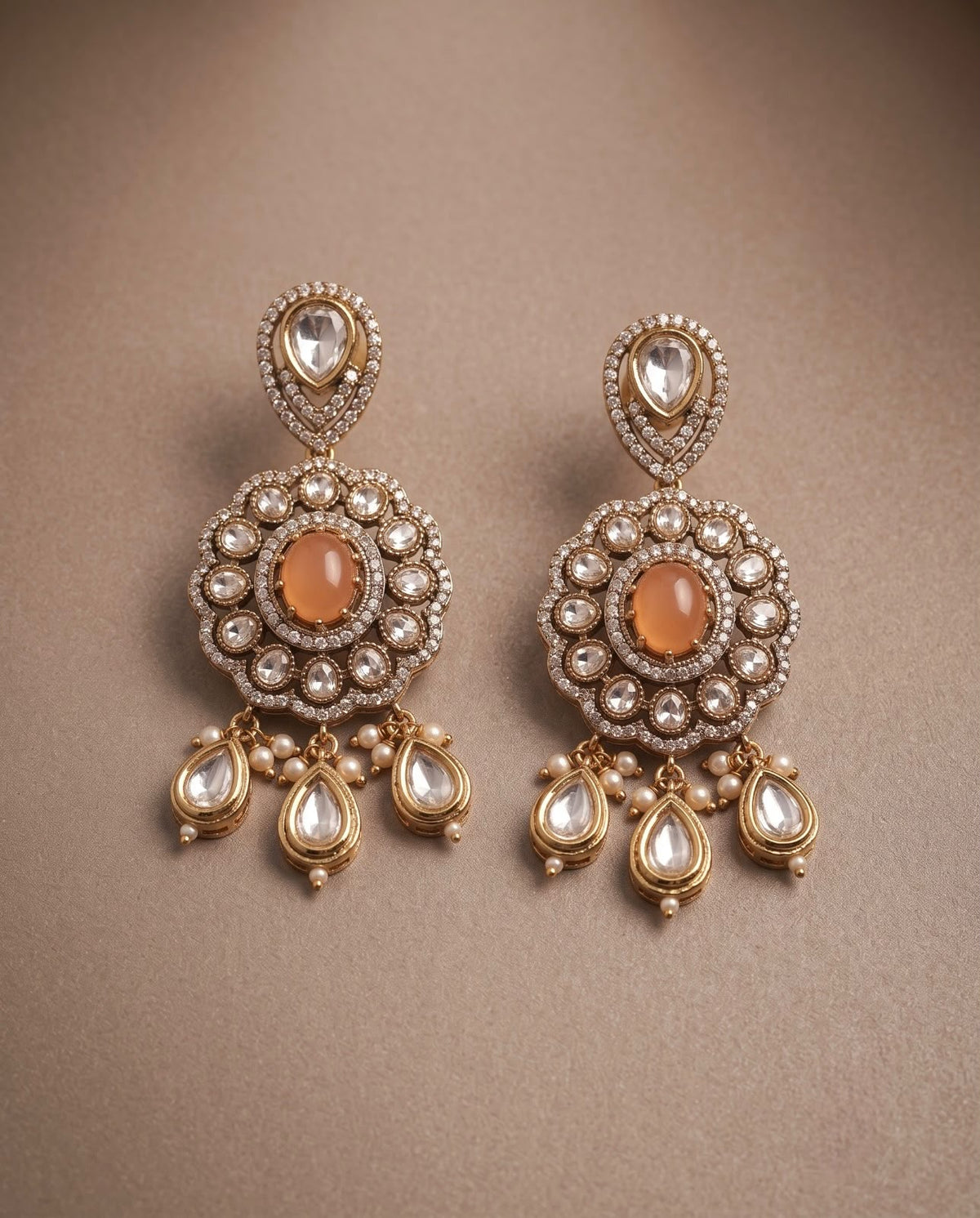 Close-up peach kundan style earrings with pearl and teardrop detailing