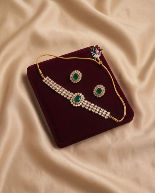 Emerald green kundan necklace set with matching earrings on burgundy velvet
