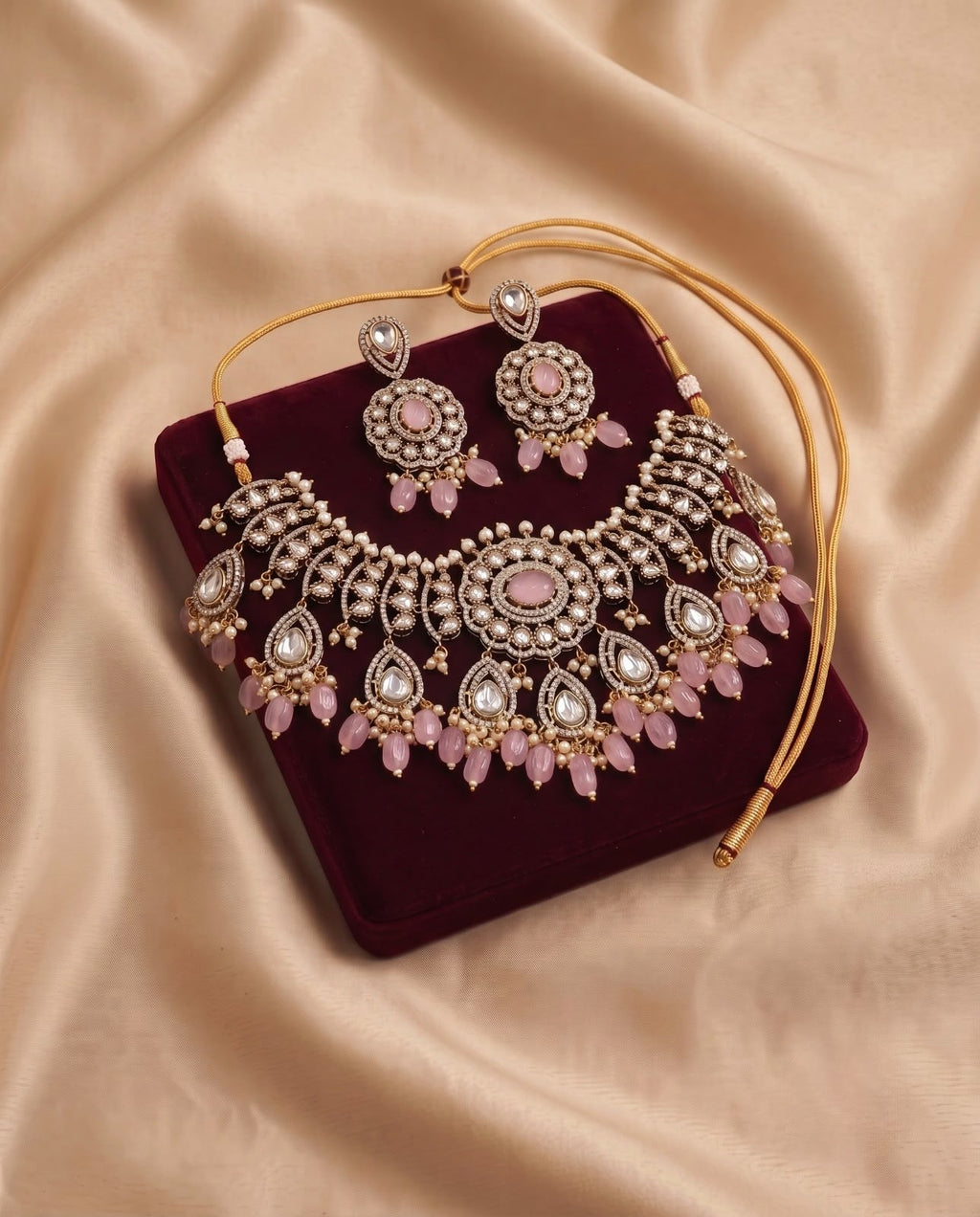 Pink kundan bridal choker necklace set with matching earrings on burgundy velvet
