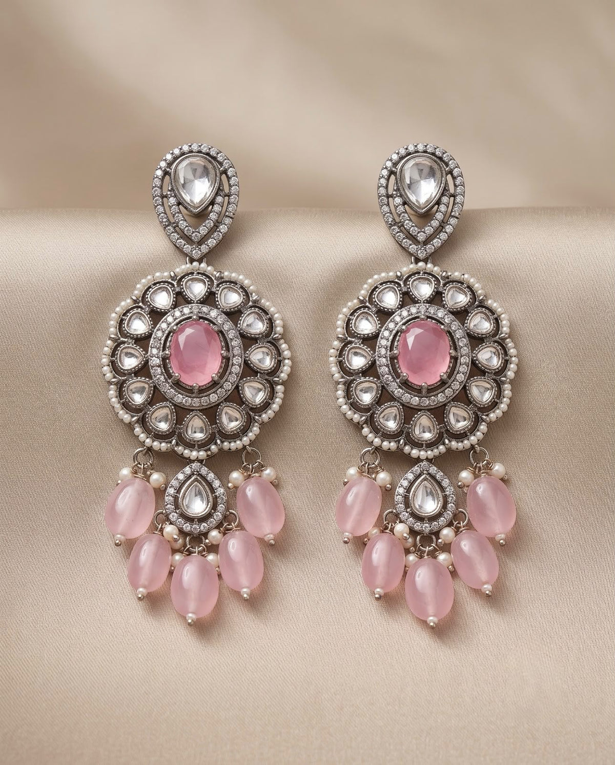 Close-up pink kundan style earrings with pearl and pink bead detailing