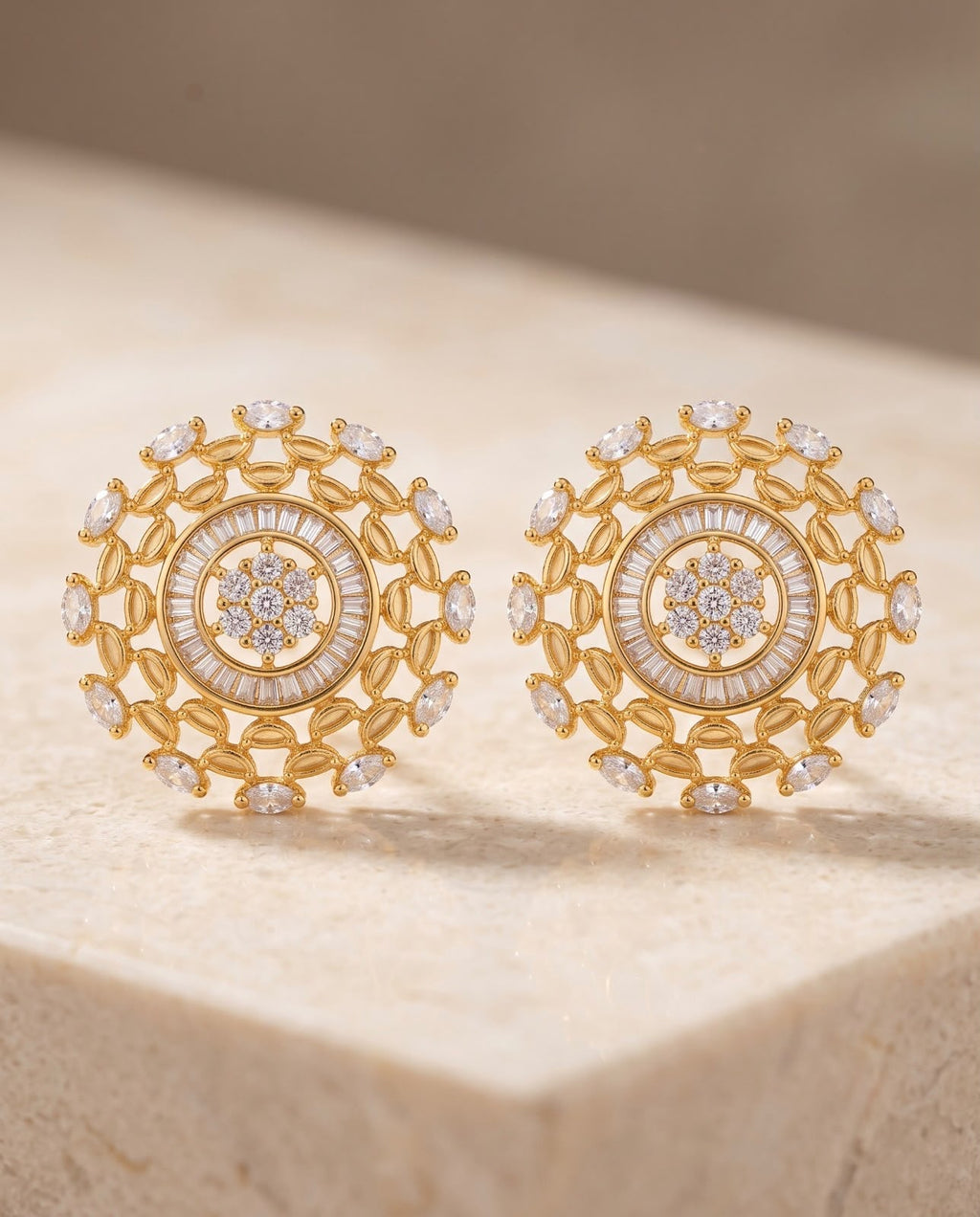 Close-up of gold geometric earrings with ruby and clear stone detailing