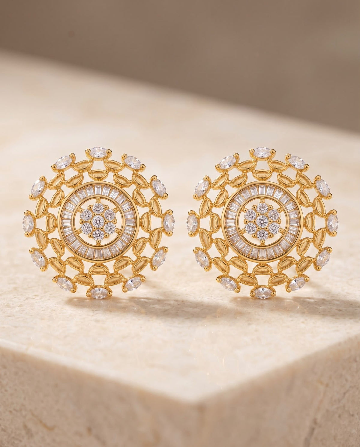 Close-up of gold geometric earrings with ruby and clear stone detailing