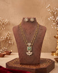 Gold-tone green stone layered necklace set displayed on jewellery bust