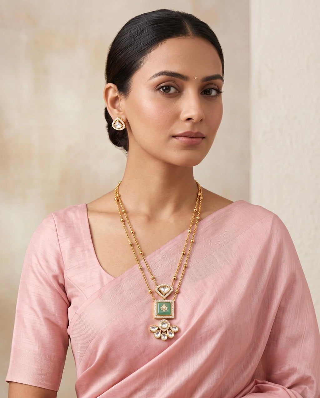 Woman wearing gold-tone green stone layered necklace set with pink saree