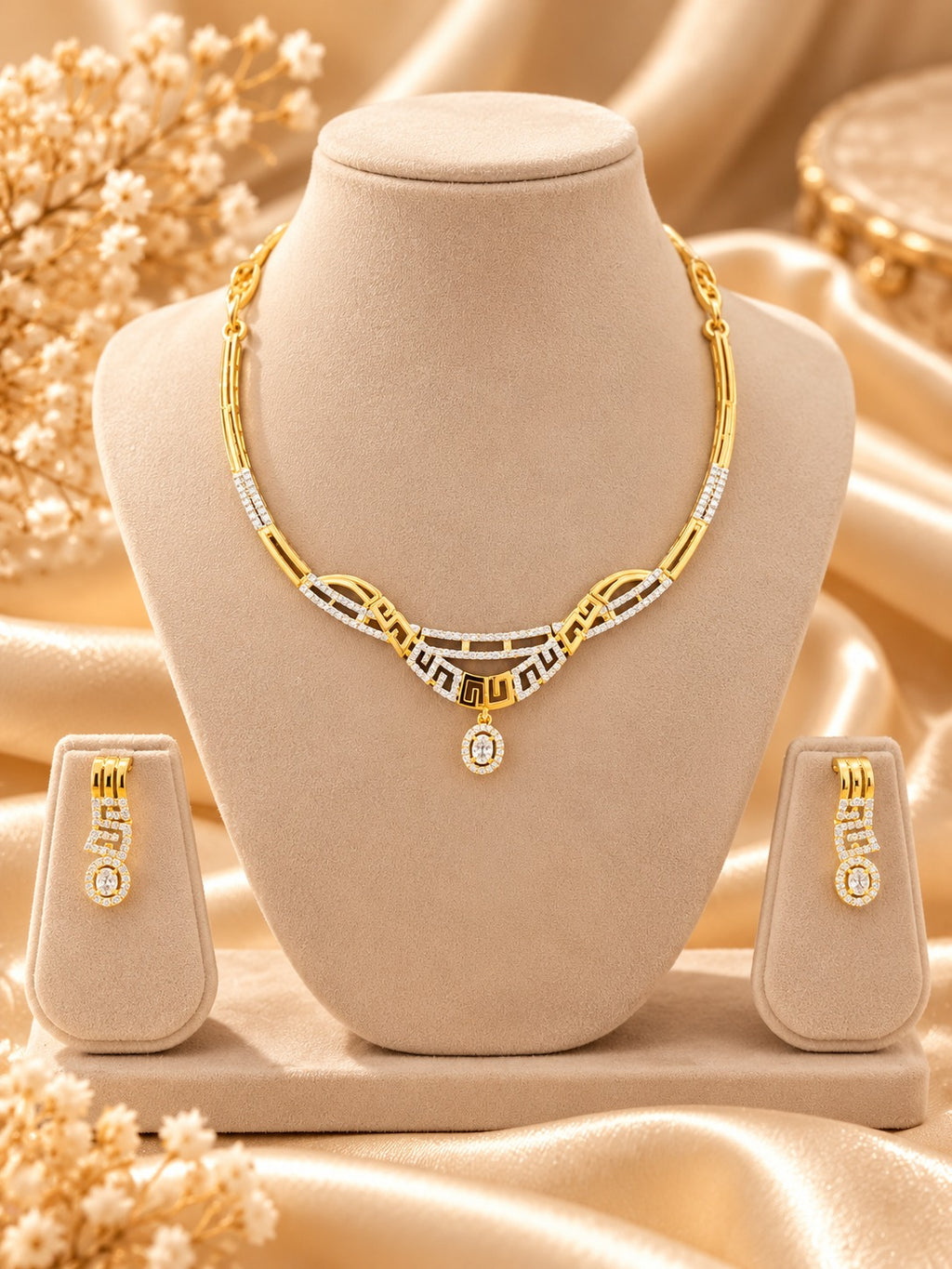 Gold-tone geometric necklace set with matching earrings on jewellery bust