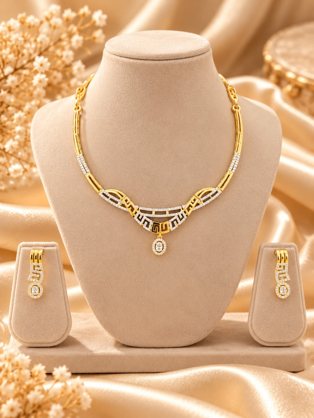 Gold-tone geometric necklace set with matching earrings on jewellery bust