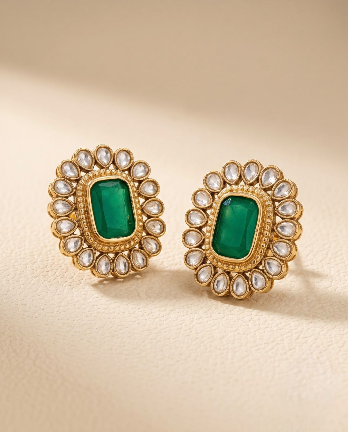 Close-up of emerald green floral stud earrings with gold-tone finish and Kundan-inspired detailing.