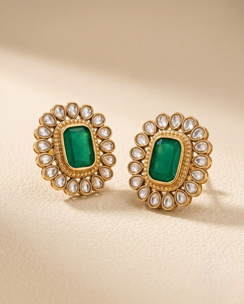 Close-up of emerald green floral stud earrings with gold-tone finish and Kundan-inspired detailing.